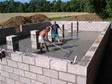 Masons working on the finishing touches of the cement floor of a crawl space foundation 