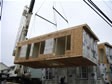 Crane lifting a well constructed modular home section on day of set with two wire straps