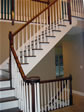 Elegant L-shaped oak foyer stair along with a custom set of stairs leading to finished basement 