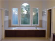 This elegant master bathroom includes a Jacuzzi tub, glass enclosed shower and specialty windows